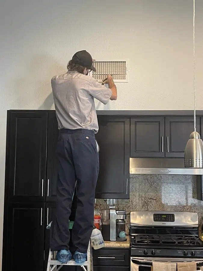 Technician inspecting an air vent during HVAC service in Oakland